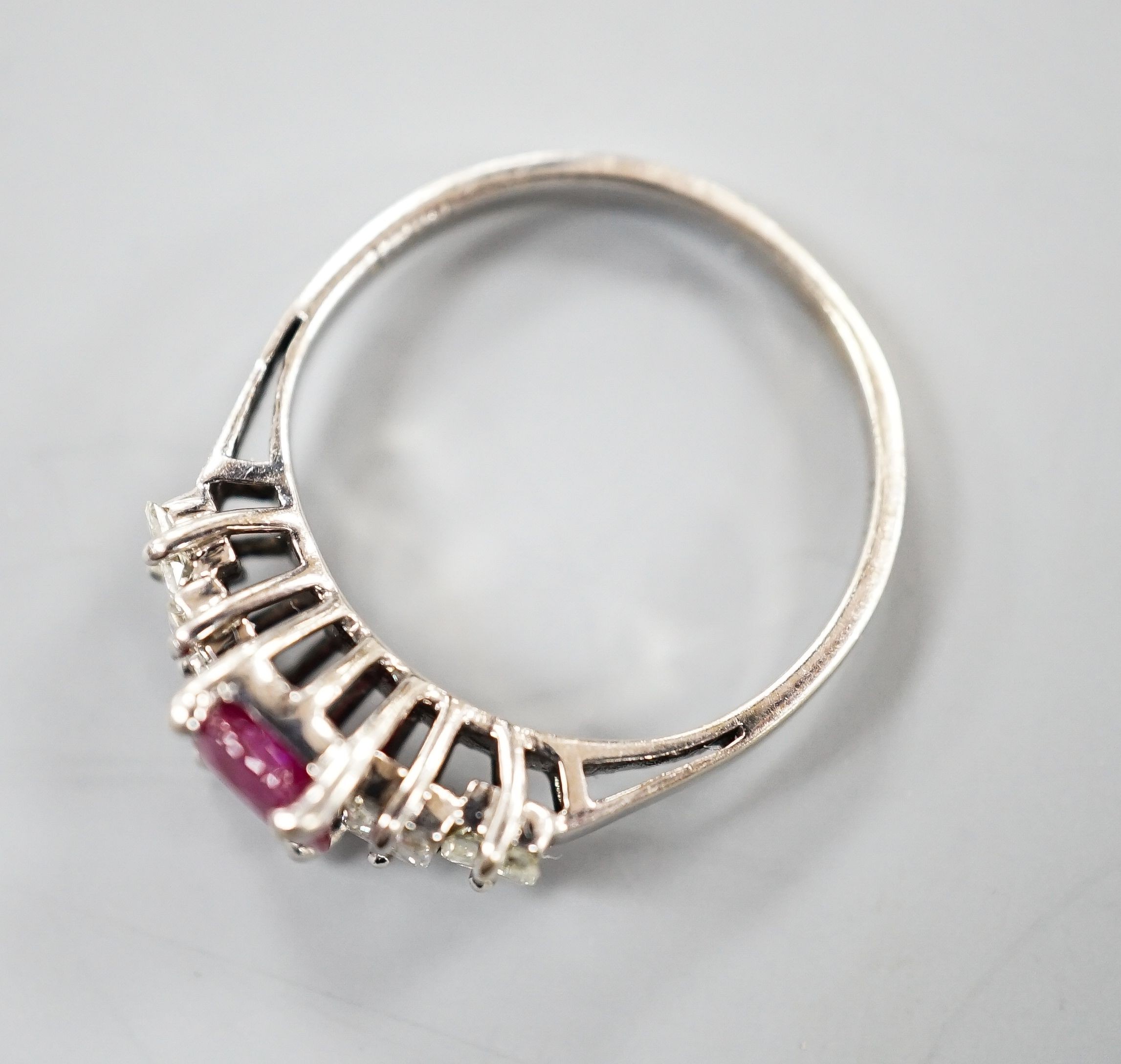 A modern 750 white metal single stone ruby and four stone princess cut diamond set half hoop ring, size M, gross weight 3.2 grams.